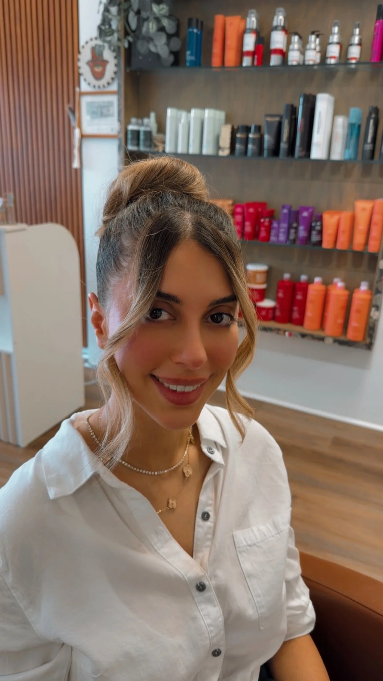 Salon Sanaa client in front of the professional hair product shelf